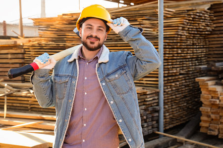 Male carpenter in hardhat with ax at sawmillの写真素材