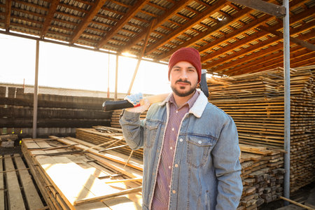Handsome carpenter with ax at sawmill