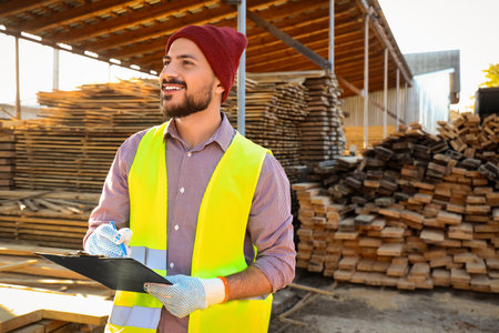 Male carpenter writing in clipboard at sawmill