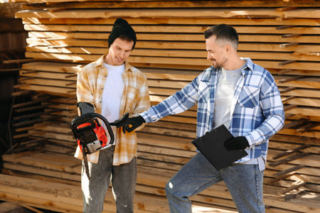Male carpenters with chainsaw at sawmillの写真素材