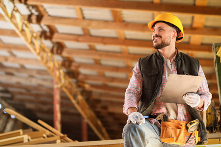 Young carpenter in hardhat with clipboard at sawmill