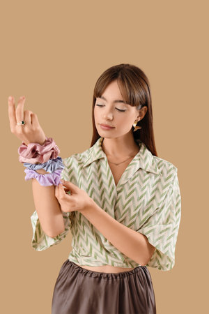 Young woman with scrunchies on beige backgroundの写真素材