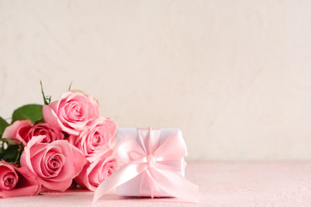 Pink roses with gift box on table against white background, closeup. Valentine's Day celebrationの写真素材
