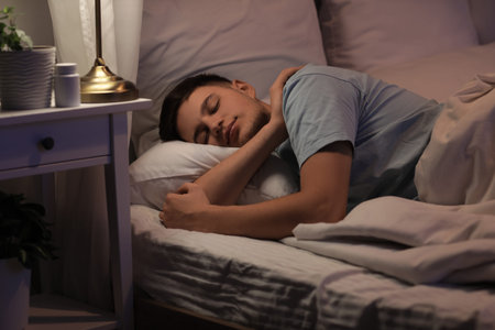 Handsome young happy man sleeping on bed in evening at home