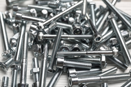 Pile of tap bolts on white wooden background, closeup