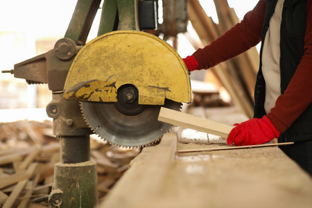 Male carpenter sawing wooden plank at sawmill, closeupの写真素材