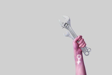 Woman with painted hand holding wrenches on light background. Feminism conceptの写真素材