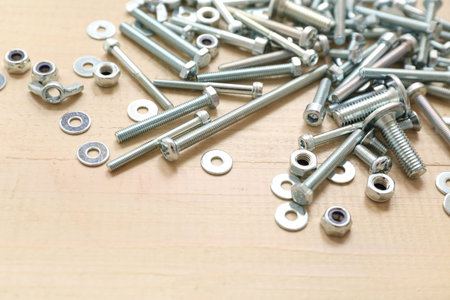 Tap bolts, chrome nuts and washers on wooden background