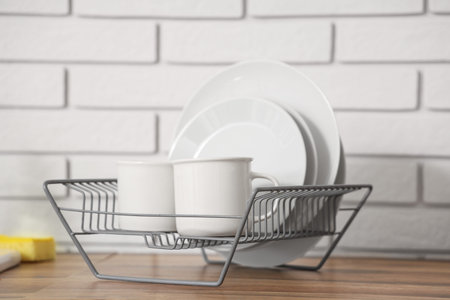 Metal rack with clean plates and cups on wooden kitchen counterの写真素材