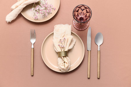 Beautiful table setting with cutlery and flowers on brown backgroundの写真素材