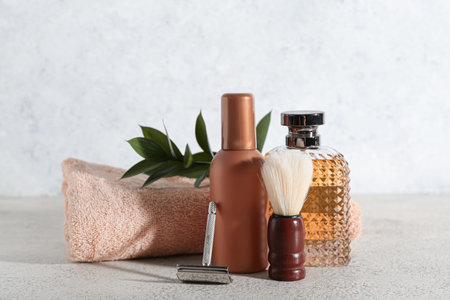 Set of men's shaving accessories with plant branch on light grunge table, closeup