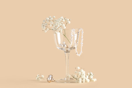 Beautiful flowers, glass and jewelery on beige backgroundの写真素材
