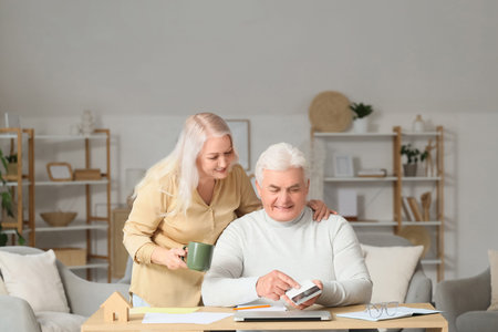 Senior man with his wife calculating utility bills at homeの写真素材