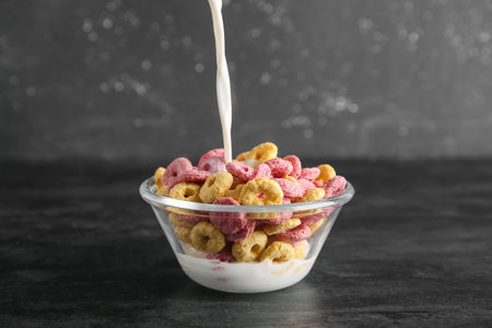 Bowl with color cereal rings and milk on black grunge background