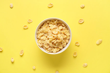 Bowl with healthy cornflakes on yellow background