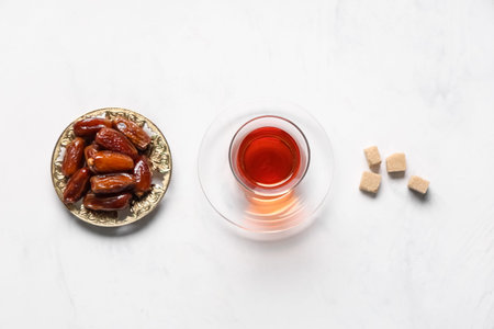Glass of Turkish tea with sugar cubes and dried dates on white backgroundの写真素材