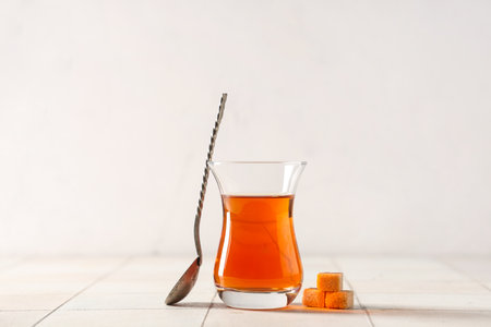 Glass of Turkish tea with spoon and sugar cubes on white tile tableの写真素材