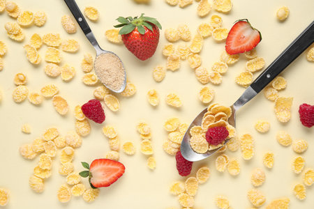 Spoons with cornflakes and strawberries on beige backgroundの写真素材