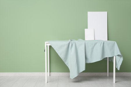 Blank frames on tablecloth near green wall in roomの写真素材
