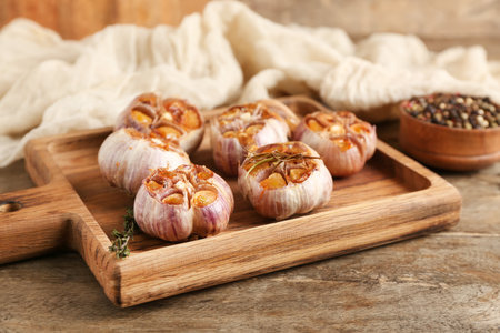 Board with baked garlic, rosemary and thyme on wooden backgroundの写真素材