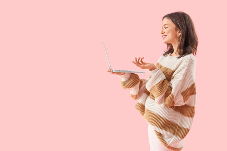 Young woman with laptop video chatting on pink background. Online dating conceptの写真素材