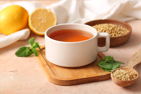 Cup of hot buckwheat tea with mint leaves and wooden spoon on beige grunge backgroundの写真素材