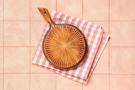 Empty cutting board with napkin on pink tiled table, top viewの写真素材