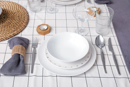 Beautiful plates on served table with stylish tablecloth. Closeup