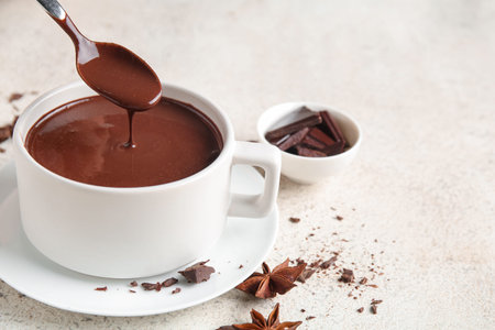 Cup of hot chocolate with spoon on white grunge background