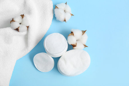 Cosmetic pads, cotton flowers and clean towel on color backgroundの写真素材
