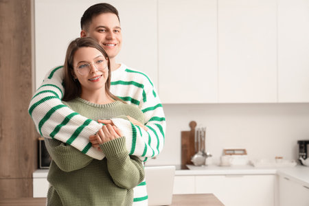 Cute young couple in warm sweaters hugging at homeの写真素材