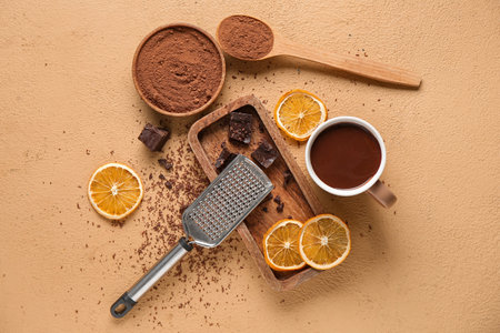 Cup of hot chocolate with cocoa powder, dried orange slices and grater on beige backgroundの写真素材