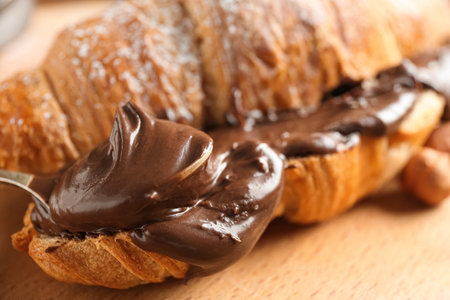 Sweet croissant with chocolate spread on wooden background, closeupの写真素材