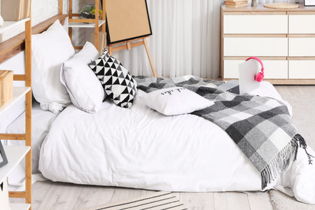 Bed with pillows and laptop in teenager's room
