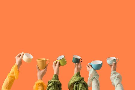 Female hands with different mugs on orange backgroundの写真素材
