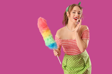 Young pin-up housewife with pp-duster on violet background
