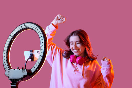 Happy female blogger recording video on color background