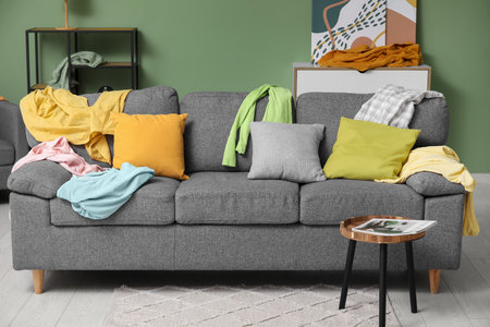Sofa with cushions and scattered clothes in living roomの写真素材