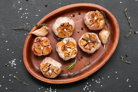 Baking dish with garlic, rosemary and thyme on black backgroundの写真素材