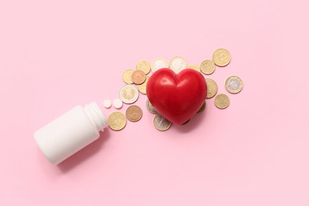 Red heart with pills and coins on pink background
