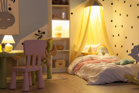 Interior of children's room with bed, shelf unit and glowing lamps at nightの写真素材