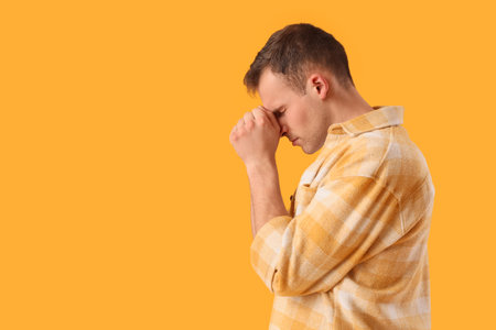 Apologizing young man on orange backgroundの写真素材