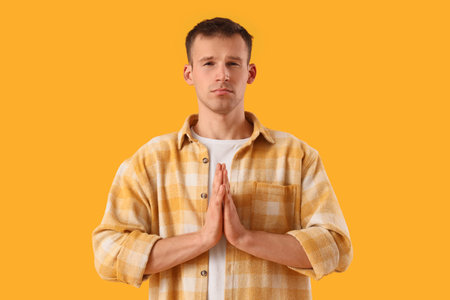 Apologizing young man on orange backgroundの写真素材