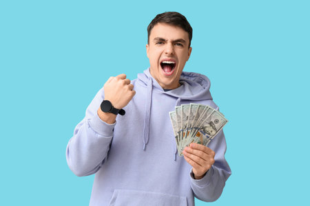 Happy young man with dollar banknotes on blue background