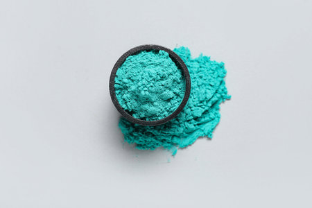 Bowl of turquoise powder pigment on light backgroundの写真素材