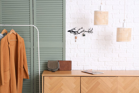 Interior of stylish hall with folding screen, wooden cabinet and key holder on white wall