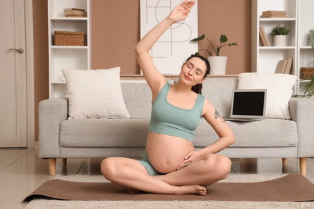 Young pregnant woman doing yoga at home