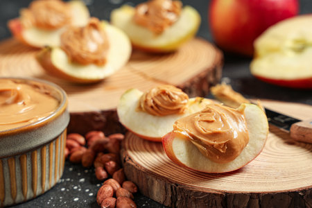 Wooden board with tasty apple wedges, nut butter and peanuts, closeupの写真素材