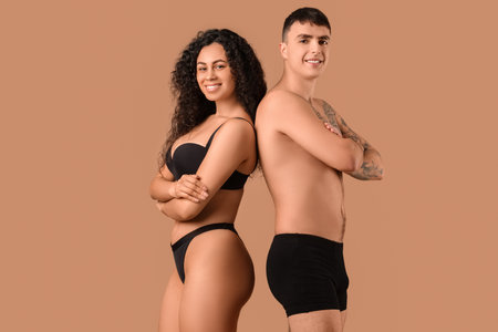 Young couple in stylish underwear on beige backgroundの写真素材