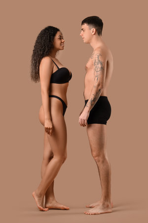 Young couple in stylish underwear on beige backgroundの写真素材